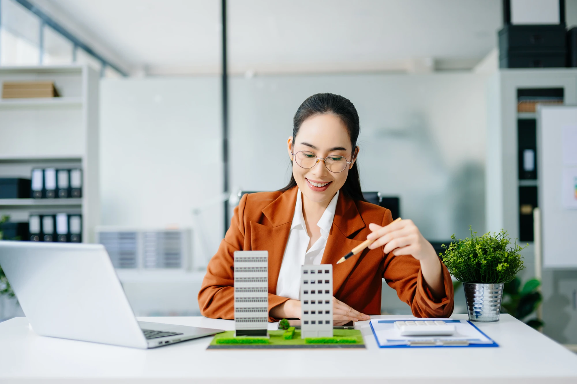 Woman examining architectural models at desk.